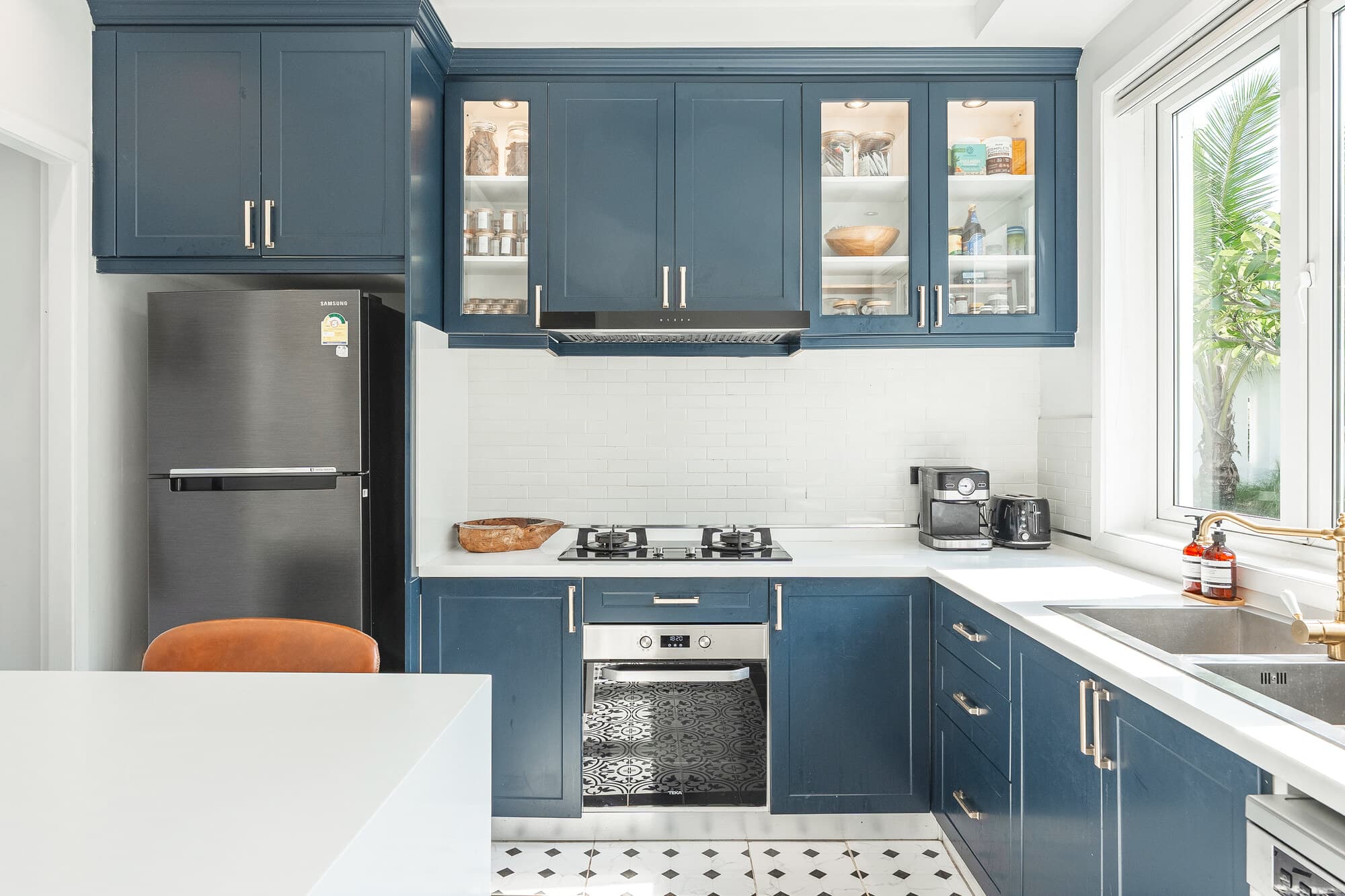 Blue and white villa kitchen with built-in appliances and garden window