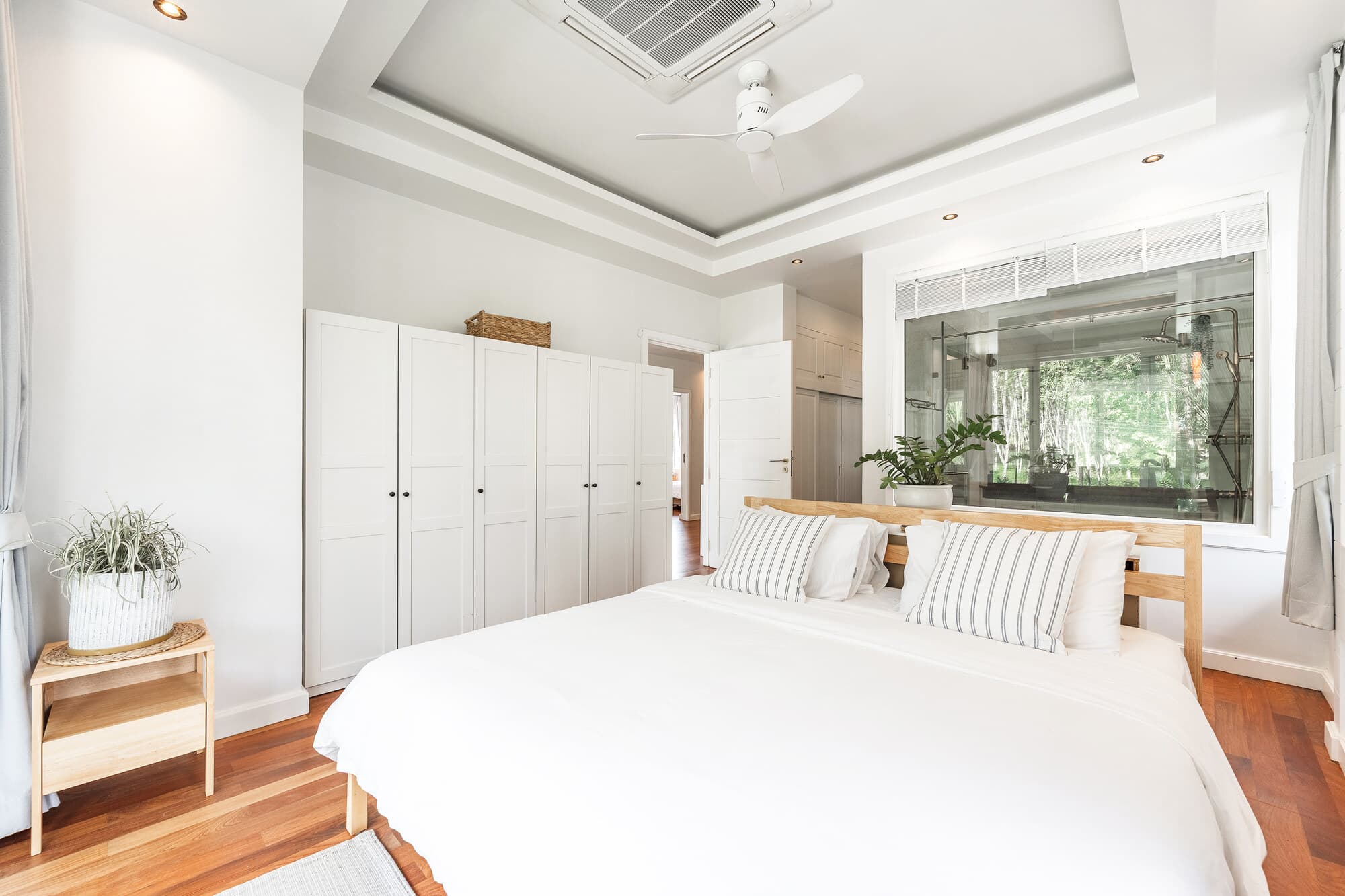 Bright master bedroom with white wardrobes and ensuite bath window