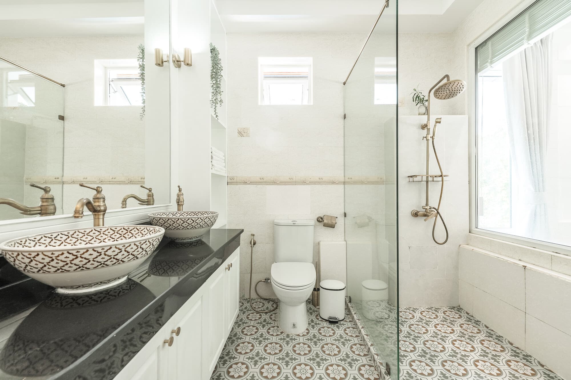 Ensuite bathroom with patterned floor tiles, double basins, and glass shower
