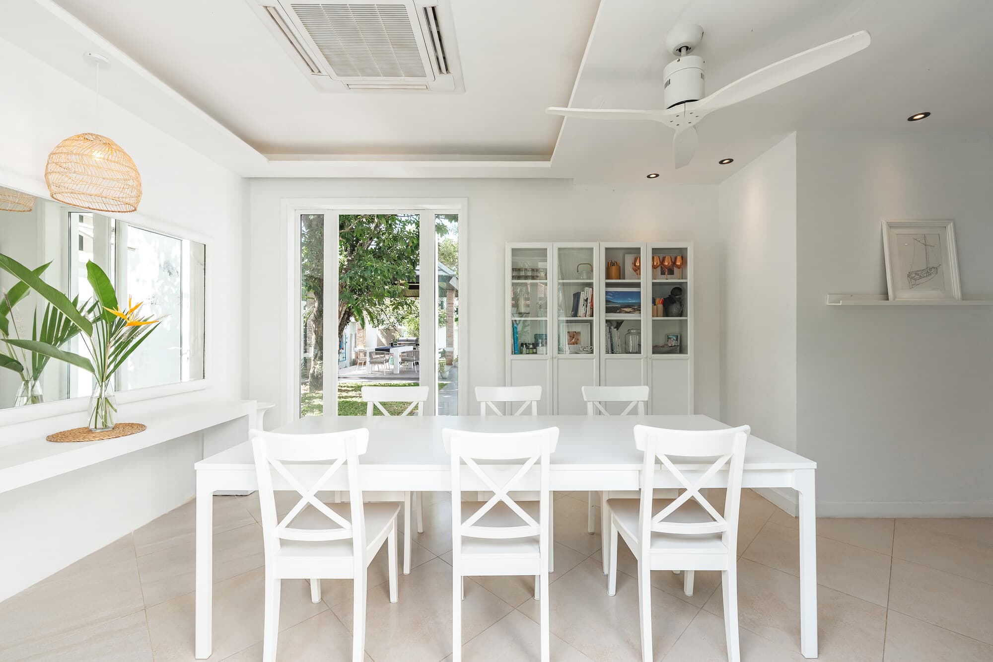 White indoor dining room with garden view through open sliding doors