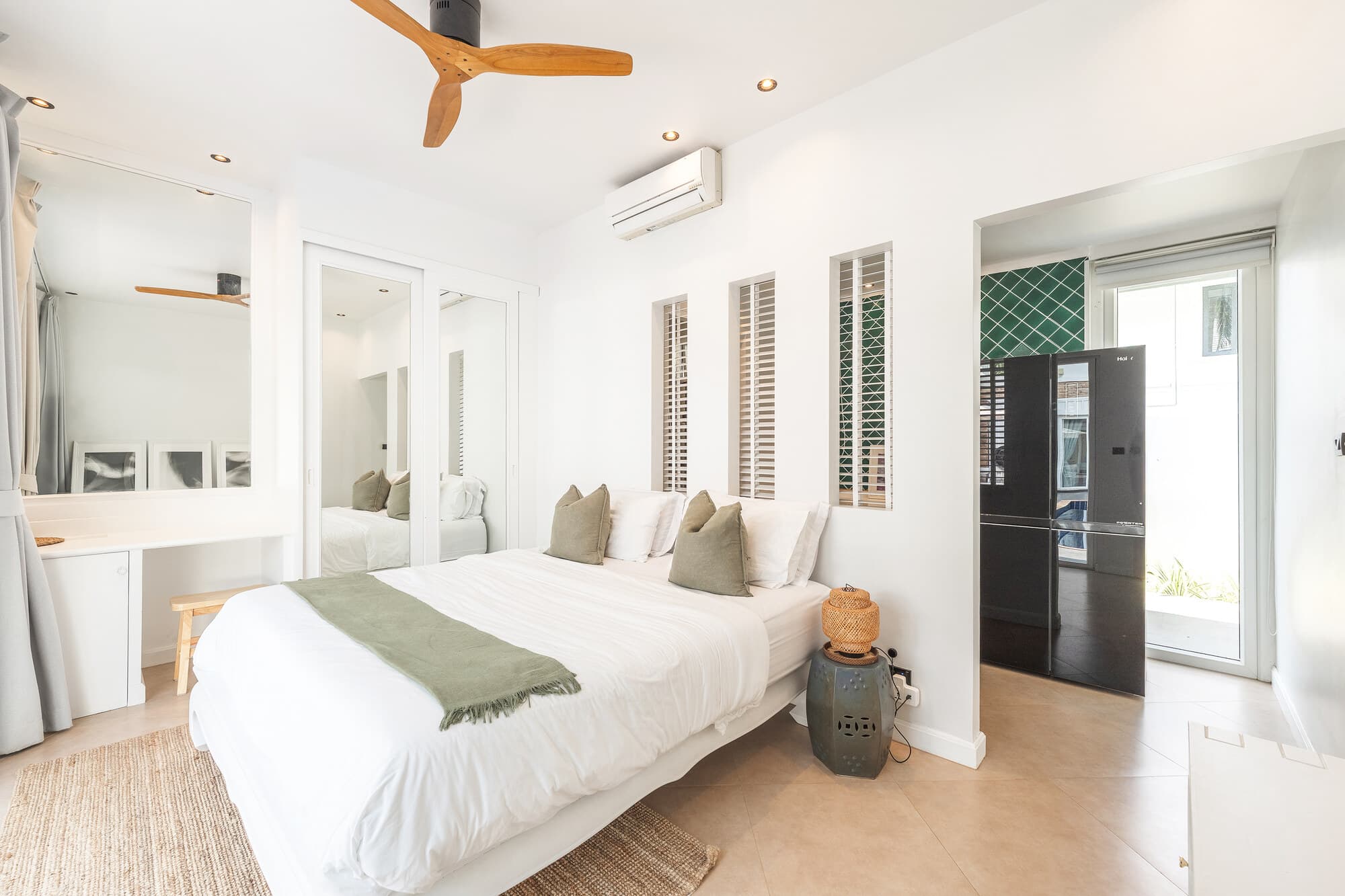 Guest bedroom with white bedding, wood fan, and view into ensuite area